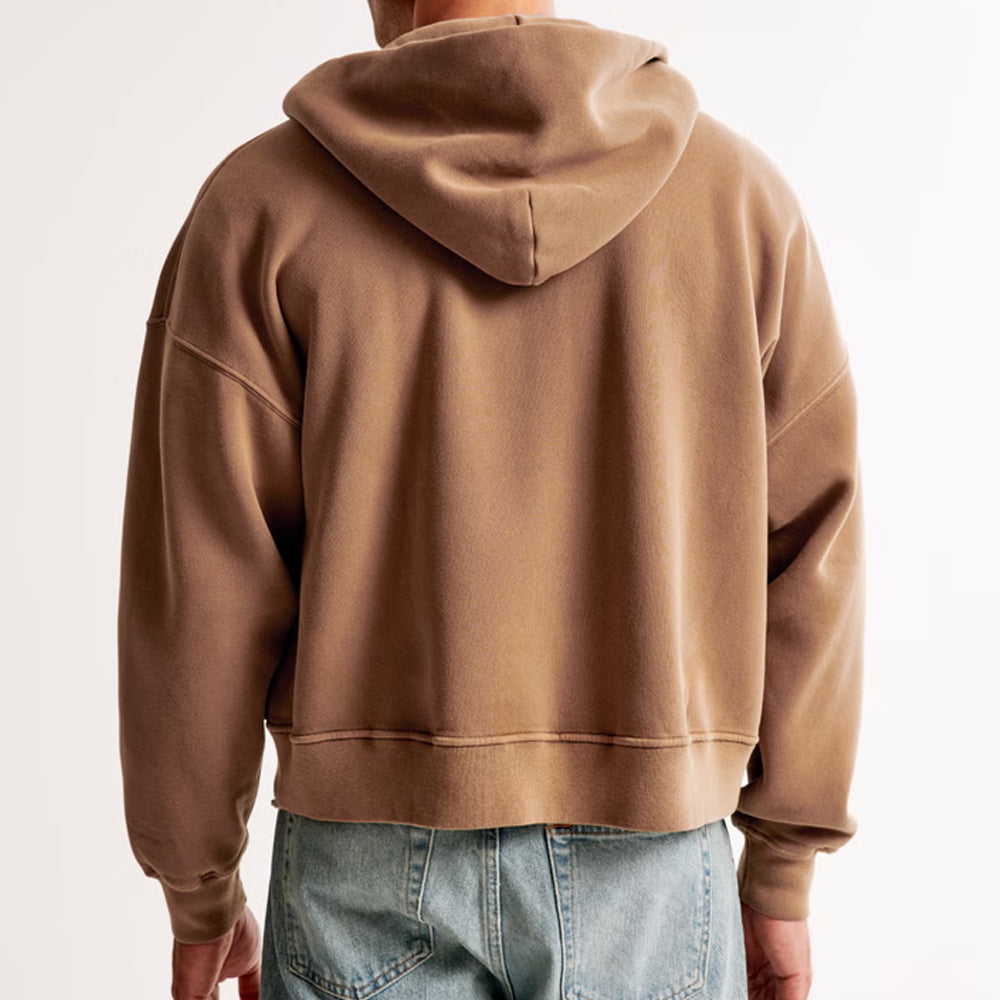 Brown hoodie worn by a person on a plain background