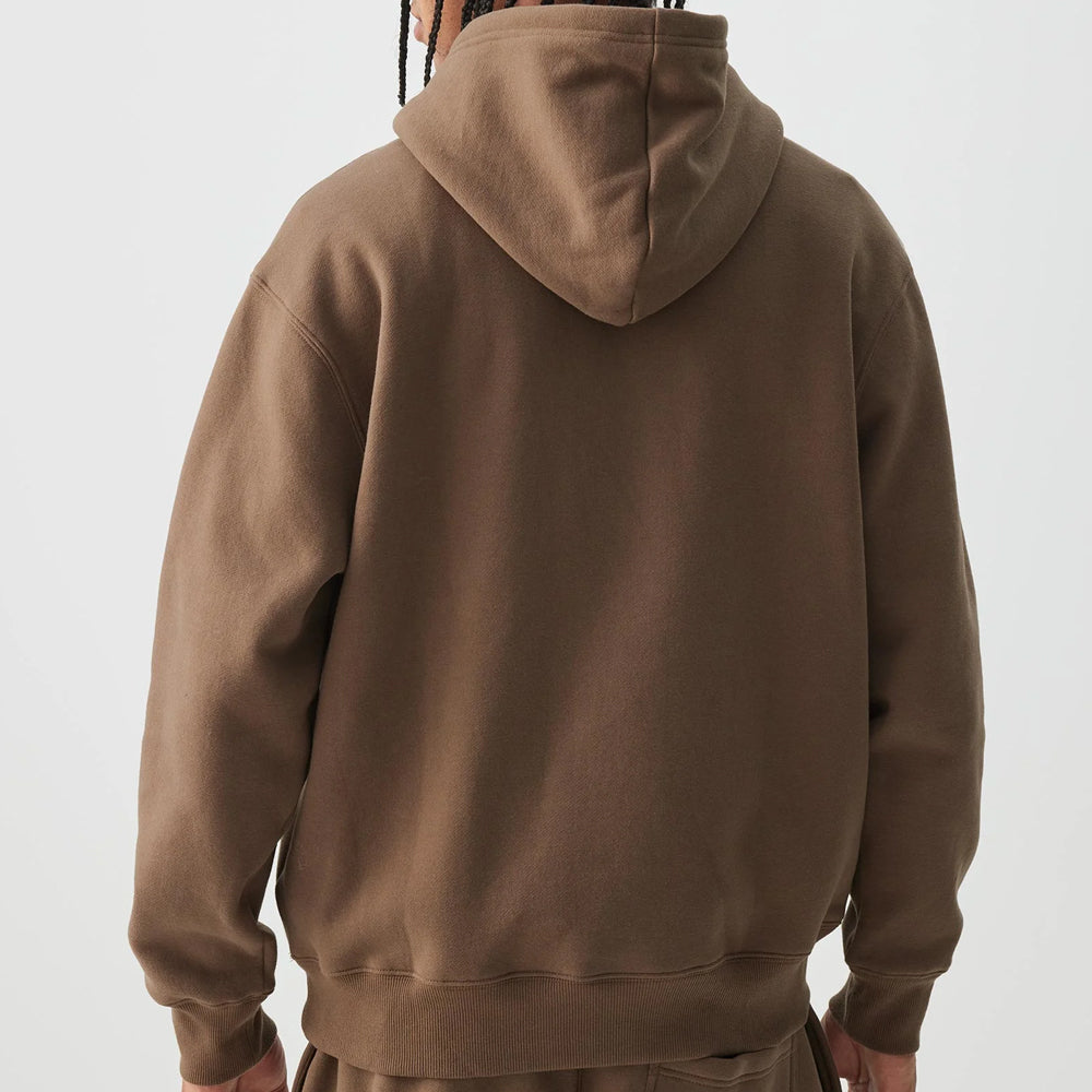Brown hoodie worn by a person on a light gray background