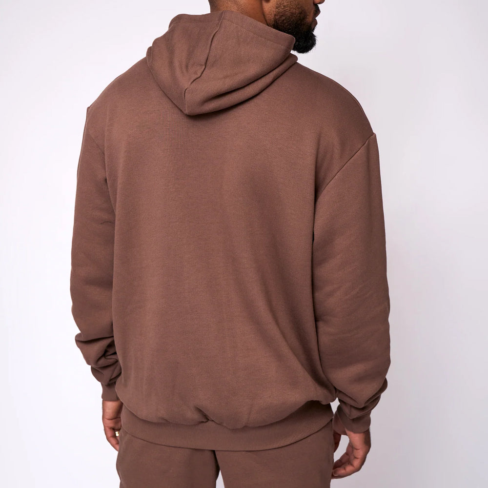 Person wearing a brown hoodie and pants on a white background