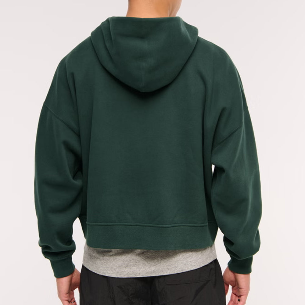 Green hoodie worn by a person on a plain background