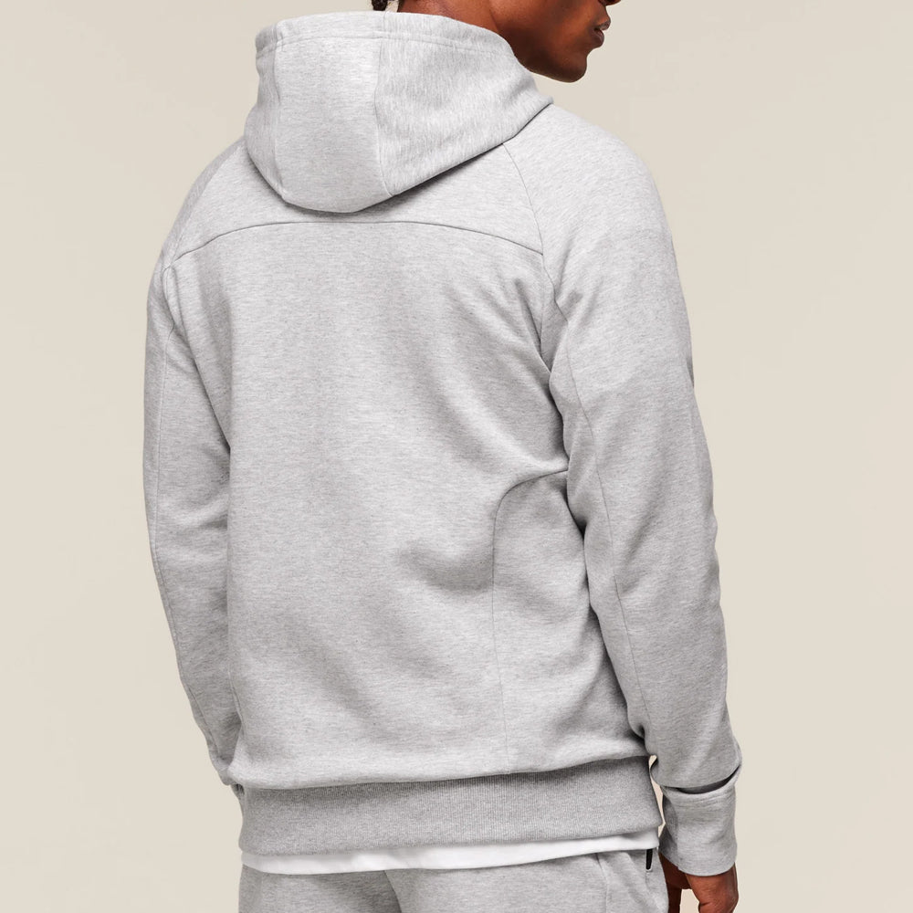 Person wearing a gray hoodie on a beige background