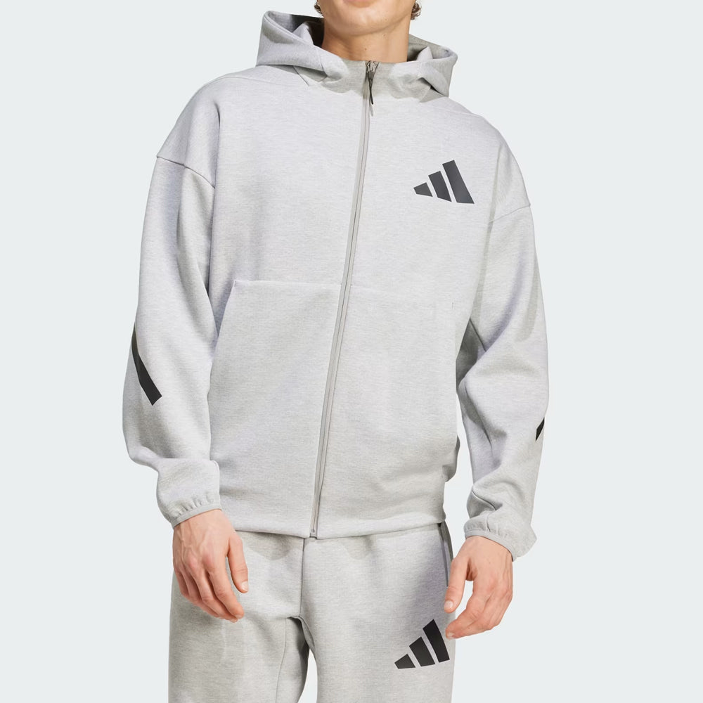 Person wearing a gray Adidas tracksuit on a white background