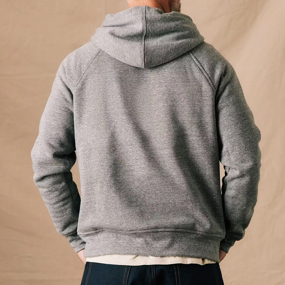 Person wearing a gray hoodie from behind on a beige background