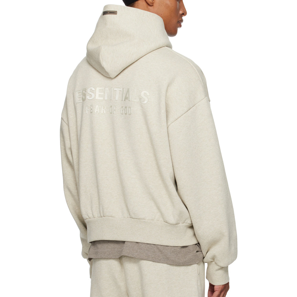 Person wearing a beige hoodie with 'Essentials' branding on the back, on a white background