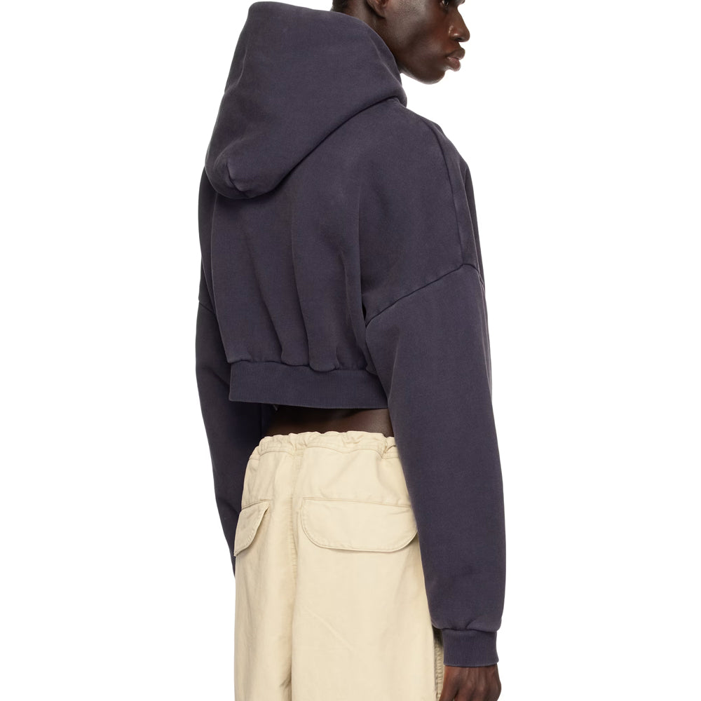 Person wearing a dark hoodie and light pants on a white background