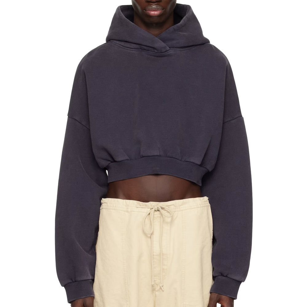 Person wearing a dark blue cropped hoodie and beige pants on a white background