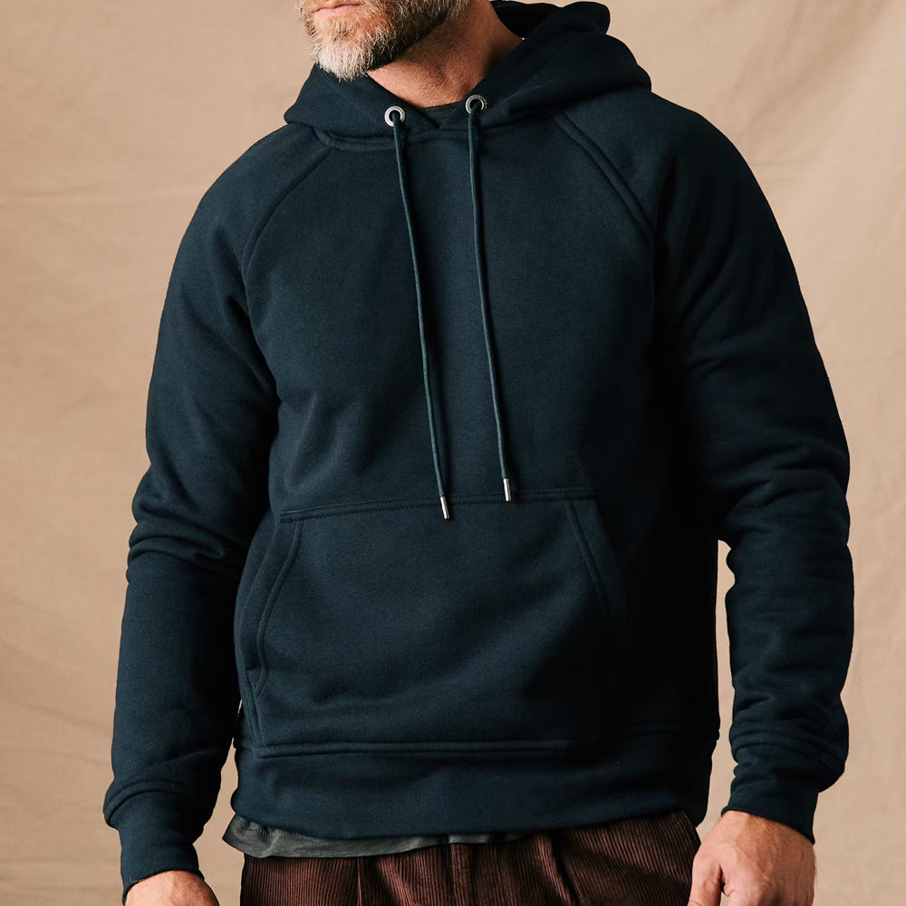 Person wearing a dark blue hoodie against a beige background