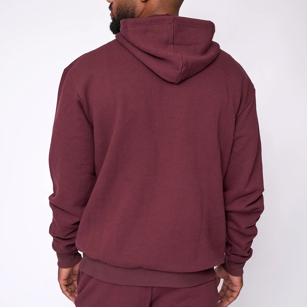 Person wearing a maroon hoodie and pants on a white background