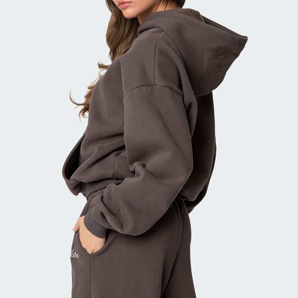 Person wearing a brown hoodie and pants on a light gray background