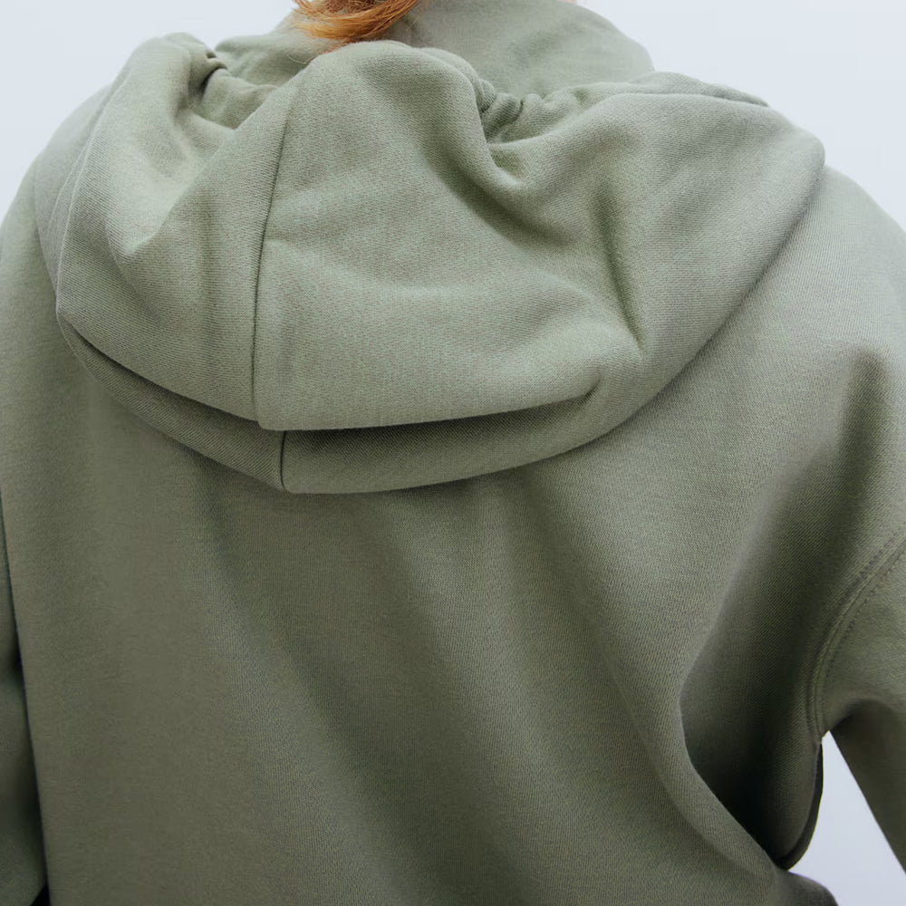 Close-up of a green hooded garment on a plain background