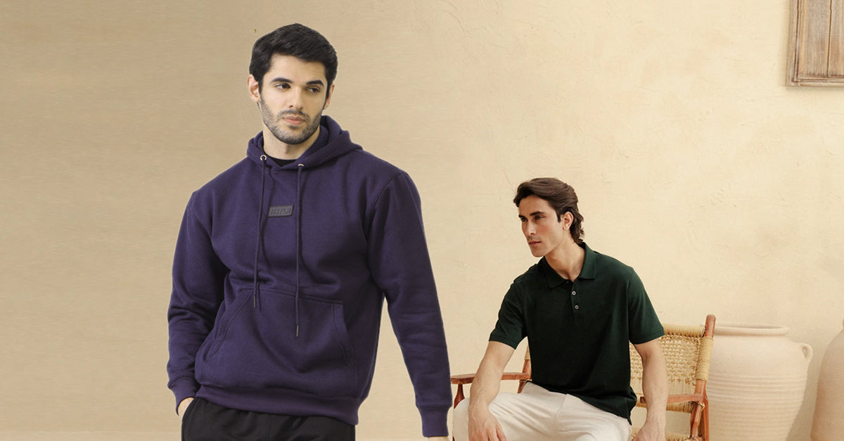 Two men wearing hoodies and a polo shirt against a beige wall.