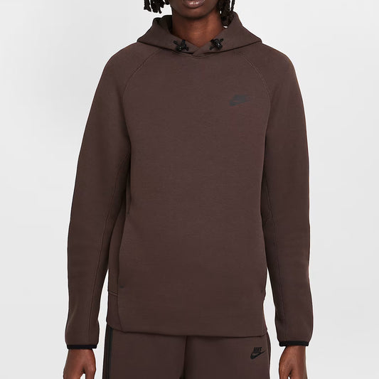 Person wearing a brown hoodie with a brand logo on a white background