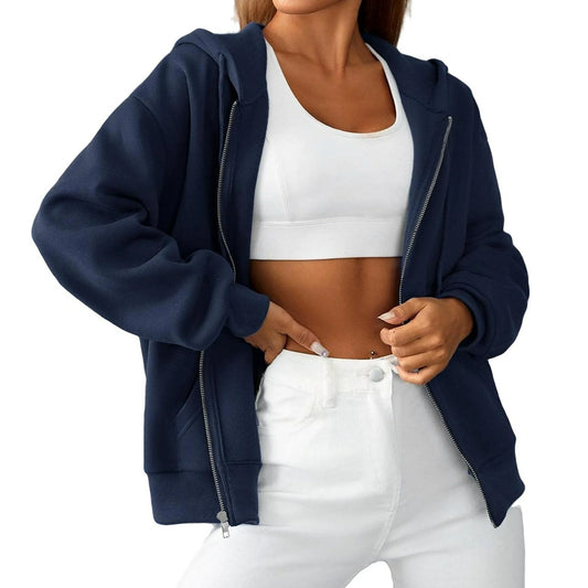Person wearing a navy blue hoodie, white sports bra, and white pants on a white background