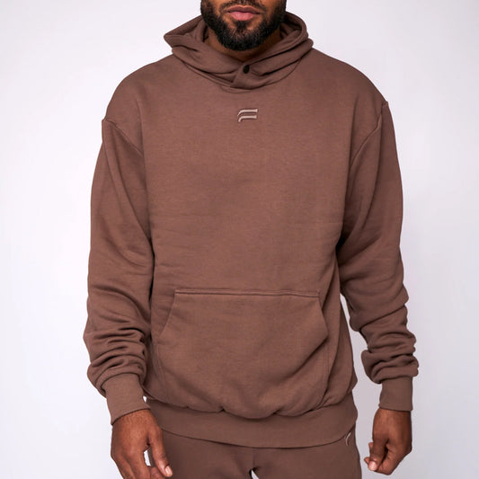 Man wearing a brown hoodie with a logo on a white background
