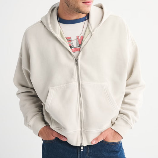 Person wearing a beige zip-up hoodie on a white background