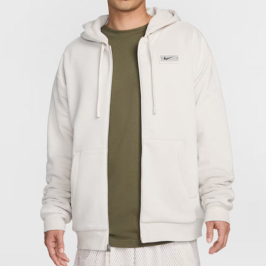 Person wearing a light gray hoodie over a green shirt on a white background