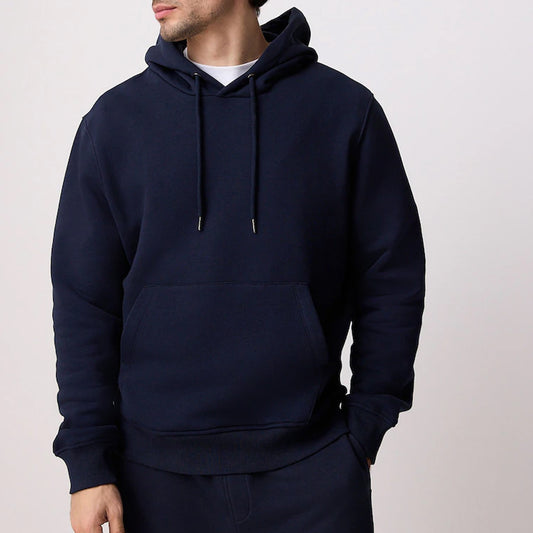 Person wearing a navy blue hoodie on a light pink background