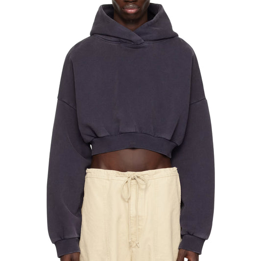 Person wearing a dark blue cropped hoodie and beige pants on a white background