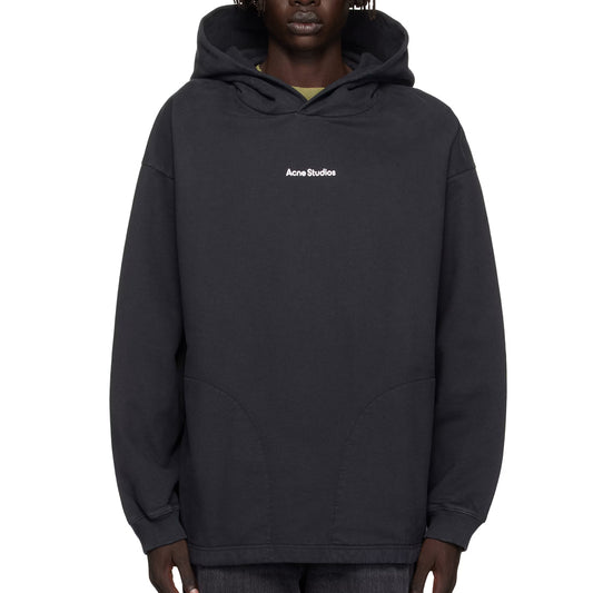 Person wearing a black hoodie with Acne Studios logo on a white background