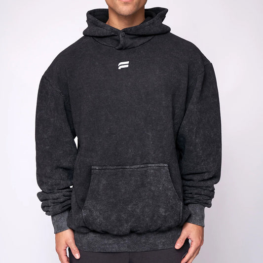 Person wearing a dark gray hoodie with a brand logo on a light gray background