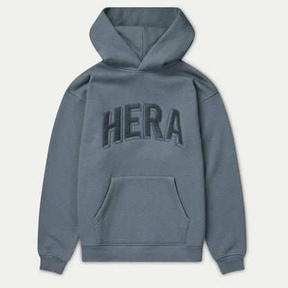 Blue hoodie with 'HERA' branding on the back against a light gray background