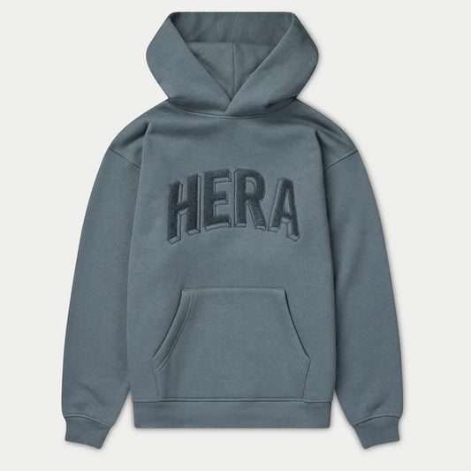 Blue hoodie with 'HERA' branding on the back against a light gray background