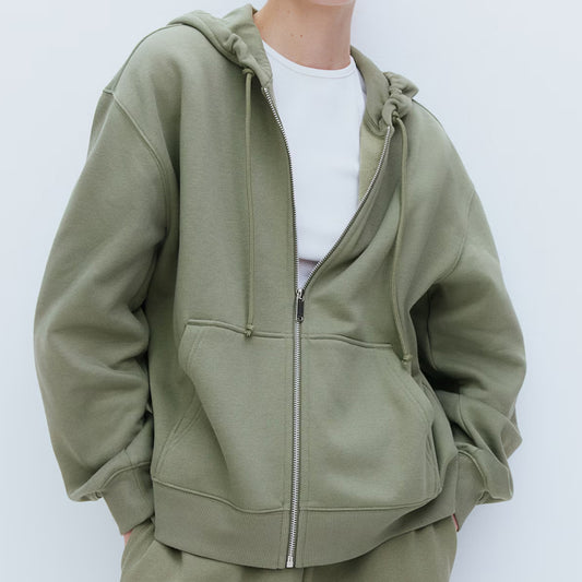 Person wearing a green zip-up hoodie on a white background